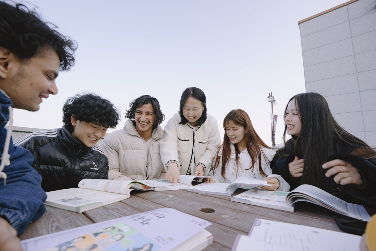 외국인 학생들과 교수님이 책을 보며 웃고 있는 사진